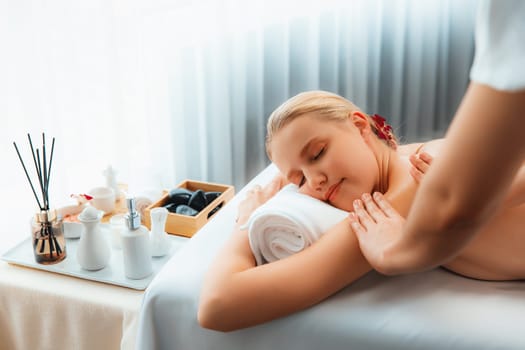 Caucasian woman customer enjoying relaxing anti-stress spa massage and pampering with beauty skin recreation leisure in day light ambient salon spa at luxury resort or hotel. Quiescent