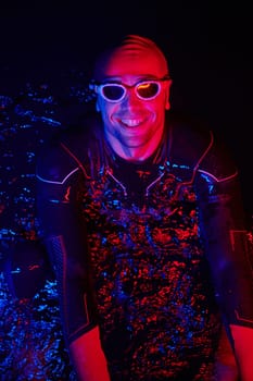 real triathlete swimmer having a break during hard training at lake on dark night neon gel color lights