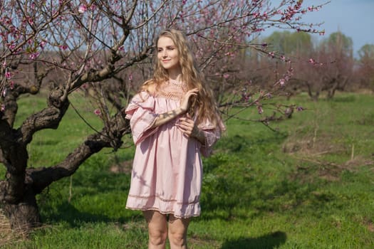 Beautiful woman in pink dress walks around the blossoming garden