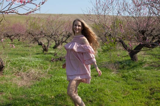 Beautiful woman in pink dress walks around the blossoming garden