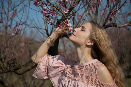 Beautiful woman in pink dress walks around the blossoming garden