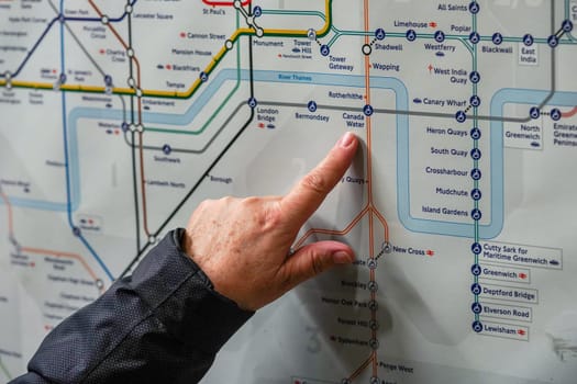 London, United Kingdom - February 02, 2019: Senior woman hand pointing to Canada Water station on London Tube map, as she plans her journey. Underground railway in UK capital serves 270 stations