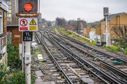 London, United Kingdom - February 01, 2019: Many railway tracks and crossings at Lewisham station on rainy day. National rail train coming in distance. Trains are used widely for transport in London