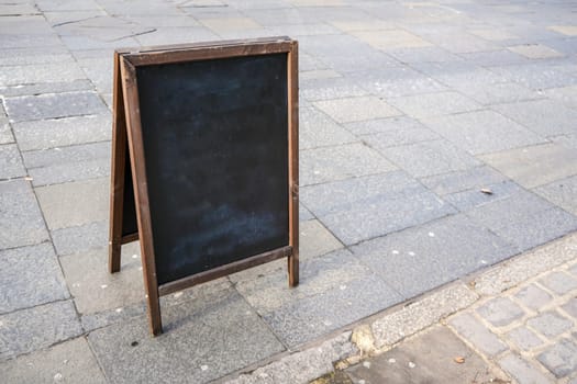 Empty blackboard on the street pavement. Mockup to add your own text.