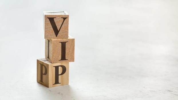 Pile with three wooden cubes - letters VIP meaning very important person on them, space for more text / images at right side.