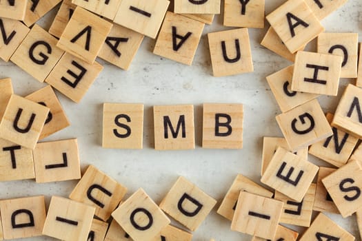 Top down view, pile of square wooden blocks with letters SMB (stands for Small to Medium Business ) on white board. 