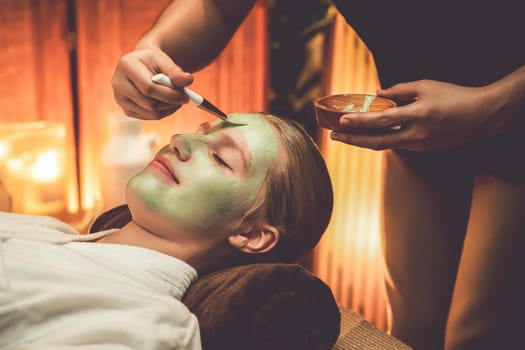 Serene ambiance of spa salon, woman customer indulges in rejuvenating with luxurious face cream massage with warm lighting candle. Facial skin treatment and beauty care concept. Quiescent