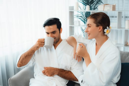 Beauty or body treatment spa salon vacation lifestyle concept with couple wearing bathrobe relaxing with drinks in luxurious hotel spa or resort room. Vacation and leisure relaxation. Quiescent