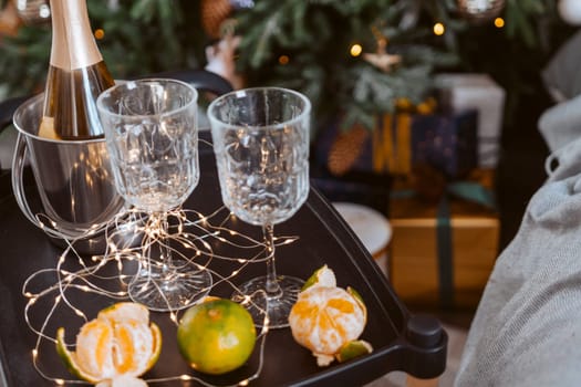 Champagne glasses, New Year decor. New Year's festive setting, family holidays.Two glasses of champagne are on the table against the background of New Year's decorated tree