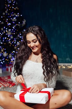 Beautiful brunette woman at christmas tree with lights garland