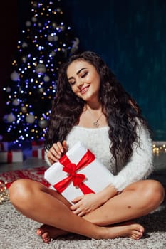 Beautiful brunette woman at christmas tree with lights garland