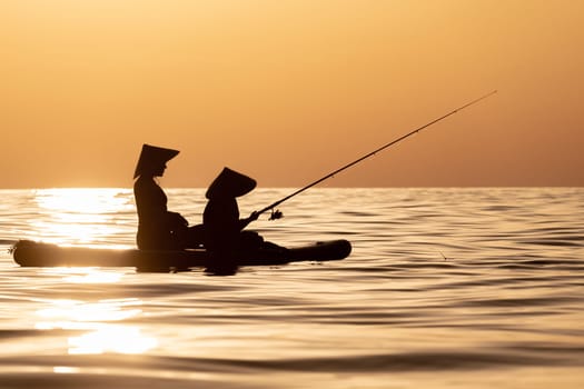 woman with a child on a sup board in the sea swim against the background of a beautiful sunset, Standup paddleboarding