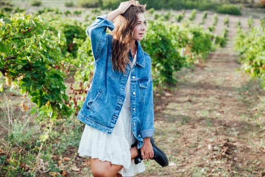 beautiful woman in white dress and denim jacket in the garden of vineyards
