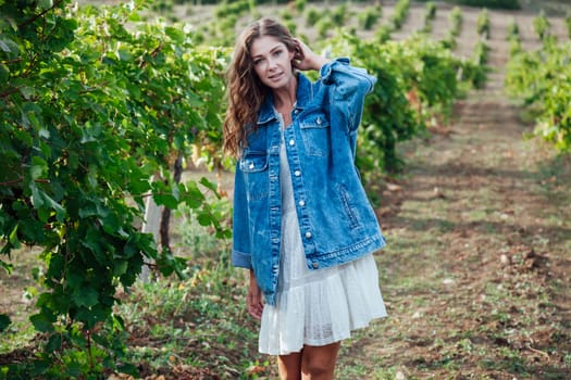 beautiful woman in white dress and denim jacket in the garden of vineyards