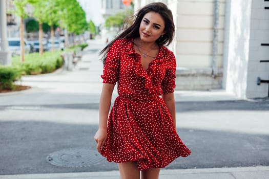 brunette woman in red polka dot dress walks the streets of the city