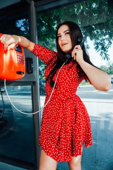 brunette woman in red dress talking in a phone booth