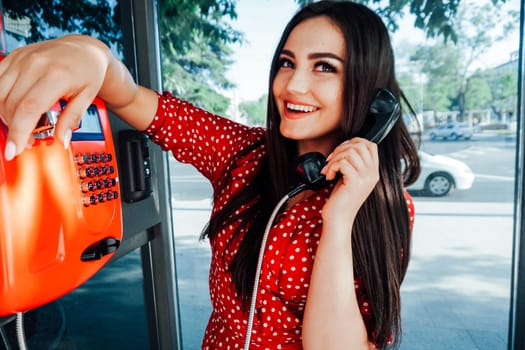 brunette woman in red dress talking in a phone booth
