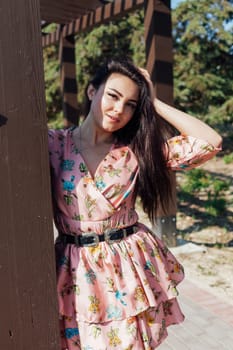 Beautiful athletic woman in dress with flowers walks in park alone