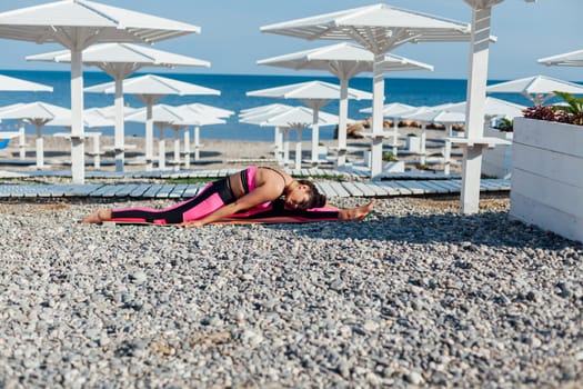 Beautiful sportswoman yoga gymnastics on the beach by the sea
