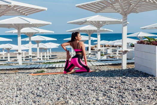 Beautiful sportswoman yoga gymnastics on the beach by the sea