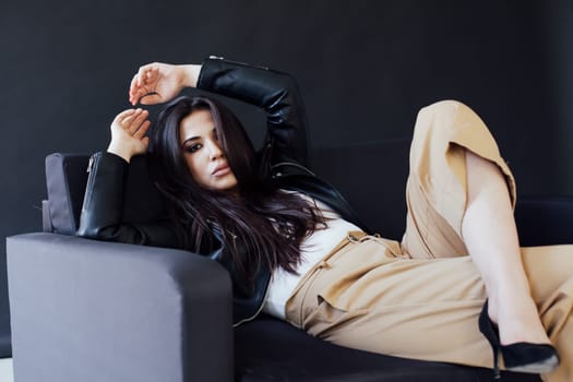 Portrait of a beautiful fashionable oriental brunette woman on a homemade black sofa