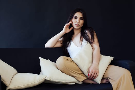 Portrait of a beautiful fashionable oriental brunette woman on a homemade black sofa