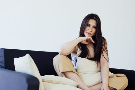 Portrait of a beautiful fashionable oriental brunette woman on a homemade black sofa