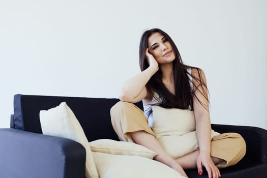 Portrait of a beautiful fashionable oriental brunette woman on a homemade black sofa