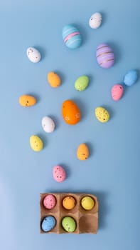Beautiful decorative multicolored eggs are scattered on a light blue background, top view.