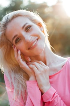 Beautiful woman in pink dress walks in the park at sunset