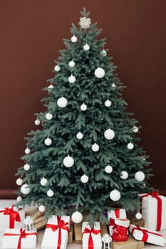 Christmas tree with presents underneath in living room. White room. Bright lights and bokeh.