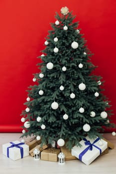 Christmas tree with presents underneath in living room. White room. Bright lights and bokeh.