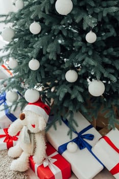 Christmas tree with presents underneath in living room. White room. Bright lights and bokeh.