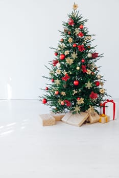 christmas tree with colorful balls and gift boxes over white brick wall