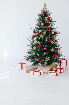 christmas tree with colorful balls and gift boxes over white brick wall