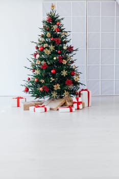 christmas tree with colorful balls and gift boxes over white brick wall