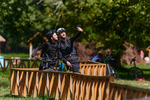 A blissful couple, adorned in professional cycling gear, enjoys a romantic bicycle ride through a park, surrounded by modern natural attractions, radiating love and happiness.