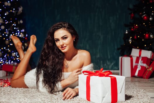 Beautiful woman opens presents at Christmas tree with garland lights