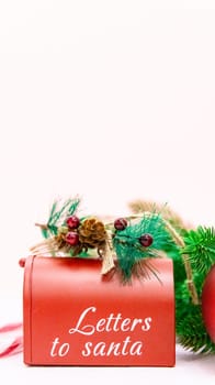 One Santa Claus mailbox with fir branches stands on a light pink textured background with copy space on top, side view close-up.