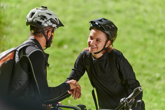 A sweet couple, equipped with bicycles and engrossed in coordinating their journey, checks their GPS mobile and watches while planning scenic routes in the park, seamlessly blending technology and outdoor adventure for a delightful cycling experience.