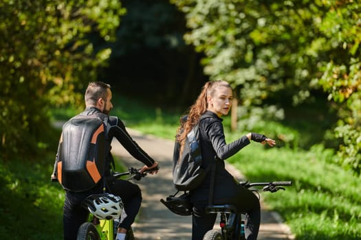 A blissful couple, adorned in professional cycling gear, enjoys a romantic bicycle ride through a park, surrounded by modern natural attractions, radiating love and happiness.