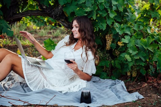 beautiful woman in white dress at a picnic with a laptop in the vineyards