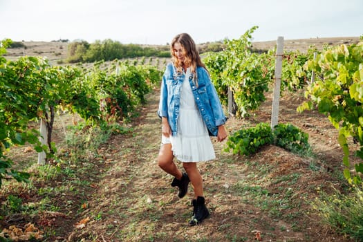 fashionable woman in a white dress and jacket in the vineyards