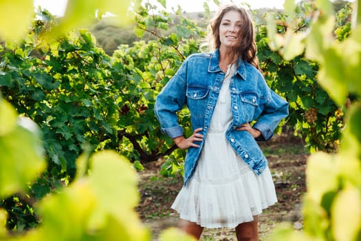 fashionable woman in a white dress and jacket in the vineyards