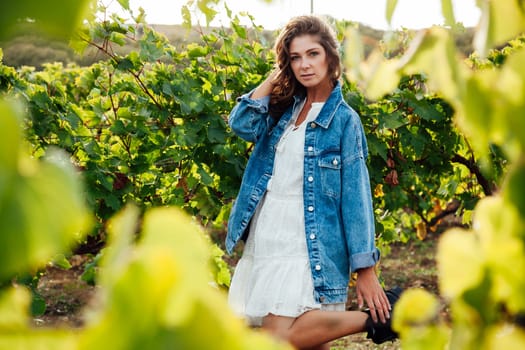 fashionable woman in a white dress and jacket in the vineyards