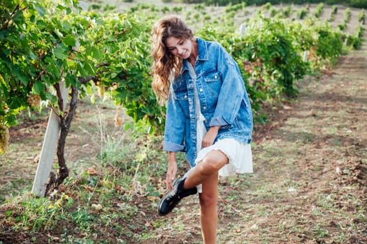 fashionable woman in a white dress and jacket in the vineyards