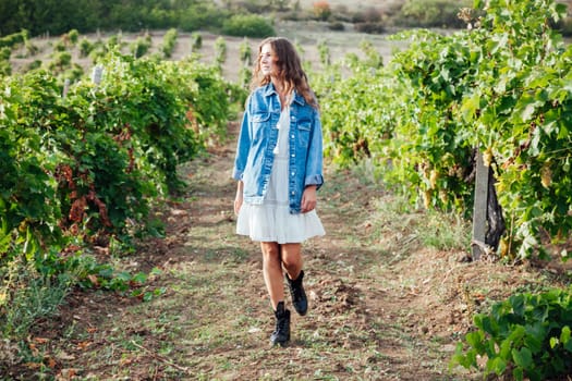 fashionable woman in a white dress and jacket in the vineyards