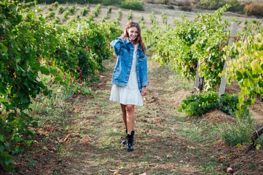 fashionable woman in a white dress and jacket in the vineyards