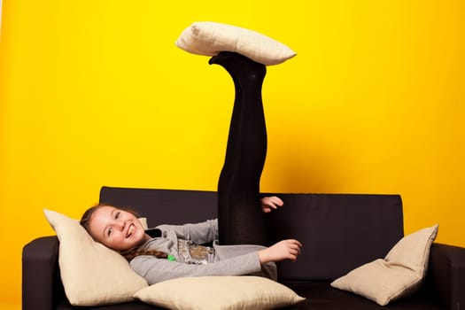 girl at home on the sofa at the yellow wall