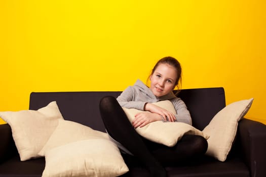 girl at home on the sofa at the yellow wall